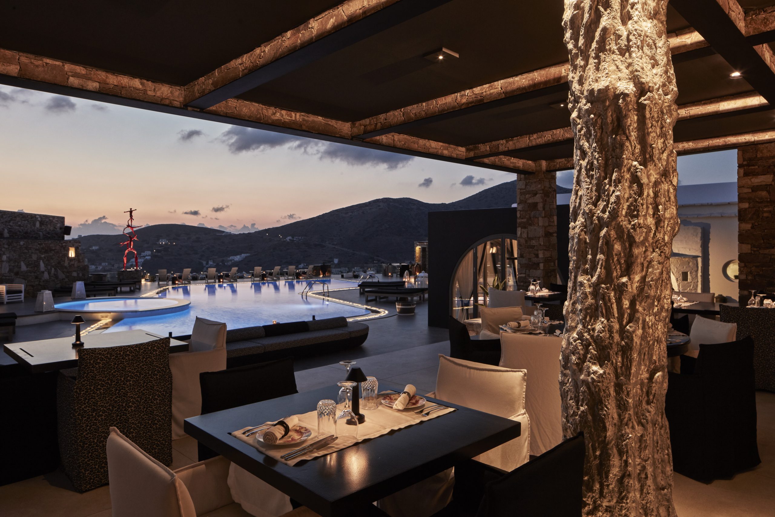 Με πανοραμική θέα το λιμάνι της Ίου και στο βάθος να αχνοφαίνεται η Σίκινος, το εστιατόριο «παίζει» με την τοπική κουζίνα των Κυκλάδων με μεσογειακές επιρροές.